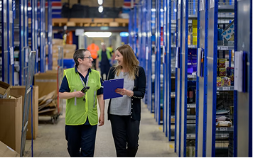 Two supervisors reviewing a paper record on a warehouse floor