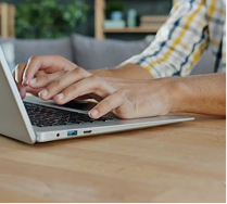A remote worker typing on a laptop at a home desk